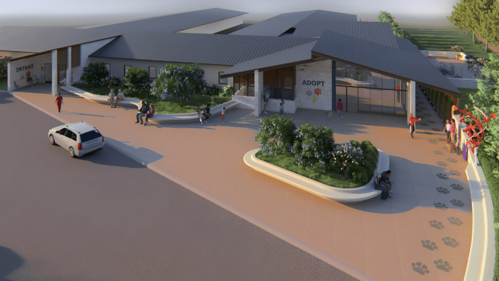 A modern animal shelter with "ADOPT" and paw prints by the entrance. People are sitting and walking outside; a white car is parked nearby. Green plants and bushes decorate the area. The sun is low, casting long shadows.