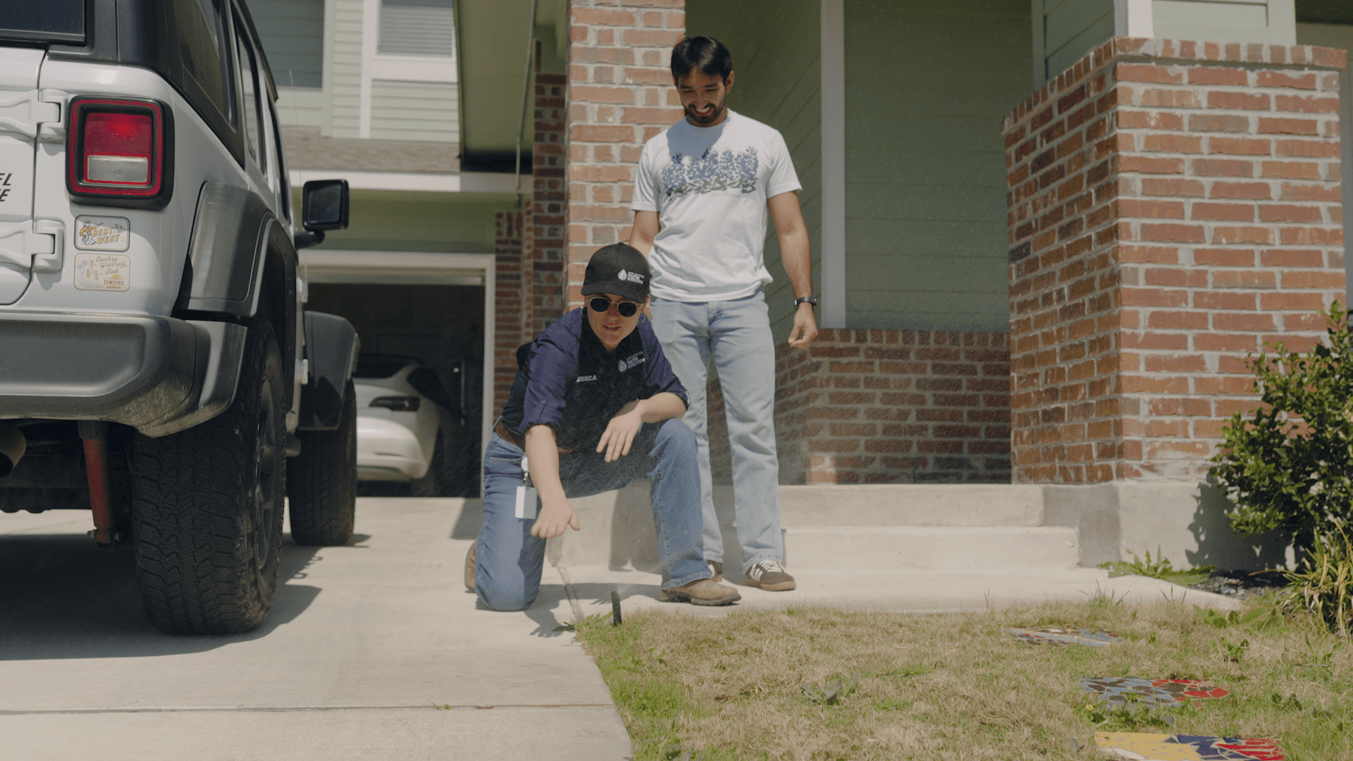Water Conservation Coordinator Jess Wright works outside a house with a City of Kyle resident as they look over their sprinkler system.