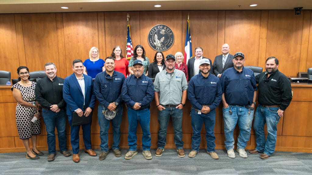 A group of City of Kyle Public Works employees pose for a photo in City Council chambers, with members of Kyle City Council during Public Works Appreciation Week.
