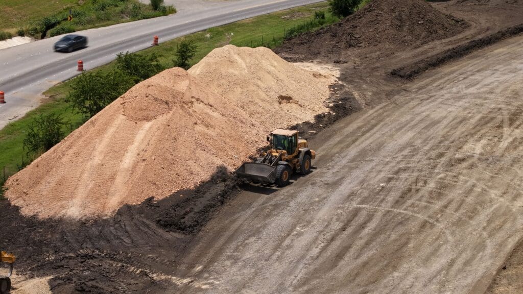 A front-end loader moves dirt along a newly cleared section of land that will eventually be the Windy Hill Road expansion in Kyle, Texas. 